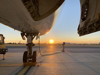 Airplane on runway against sky during sunset