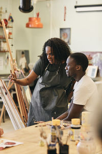 Female tutor teaching painting to young student in art class