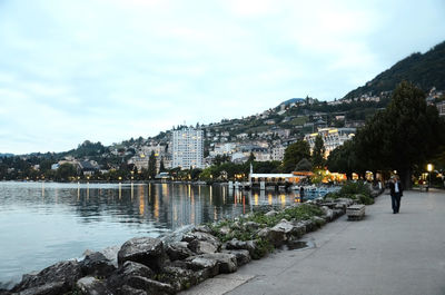 Scenic view of river by buildings against sky