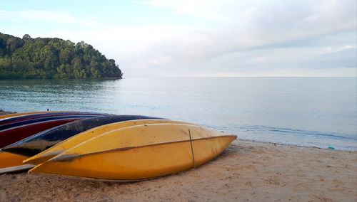 Boat moored on beach against sky