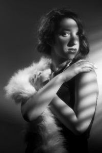 Noir style portrait of a young woman looking away against black background