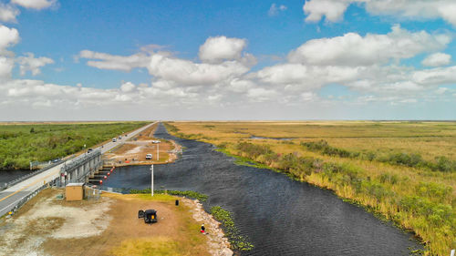 Panoramic view of road amidst field against sky