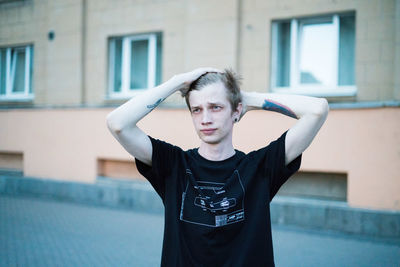 Portrait of young man standing against building