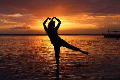 Silhouette person by sea against sky during sunset