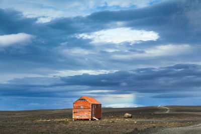 Abandoned hut against cloudy sky