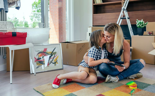 Son kissing mother on carpet at home