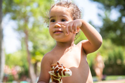 Little girl playing with her doll on the lawn of the swimming pool