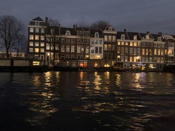 River by illuminated buildings against sky at night