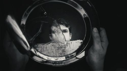 Cropped hand of man washing plate with reflection