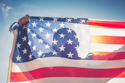 Person holding american flag against sky