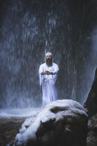 Man standing by waterfall