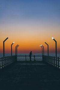 Silhouette man on beach against sky during sunset