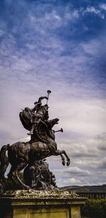 Statue in city against sky