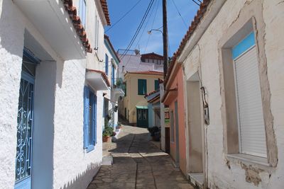 Alley amidst houses in sunny day