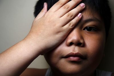 Close-up portrait of overweight boy covering eye