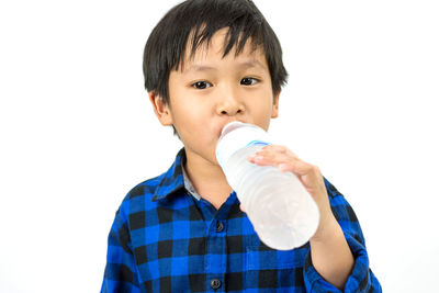 Portrait of boy drinking water against white background