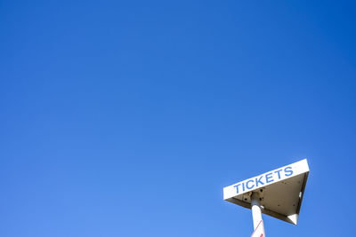 Low angle view of road sign against clear blue sky