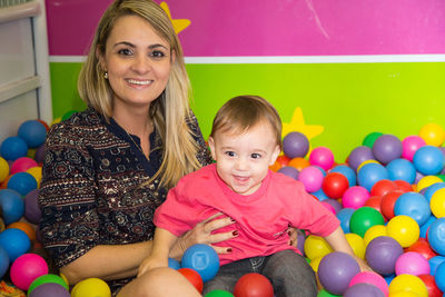 Portrait of smiling mother with son sitting in ball pool