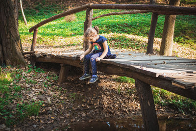 Girl sitting on footbridge in park