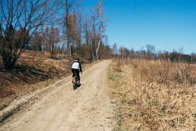 Rear view of man riding motorcycle on dirt road