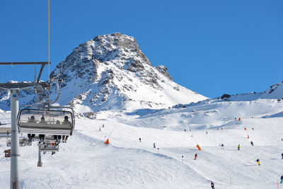 People skiing on snowcapped mountain against clear sky