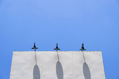 Low angle view of birds flying against clear blue sky