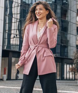 Beautiful young woman standing against wall in city