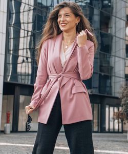 Beautiful young business woman standing against wall in city