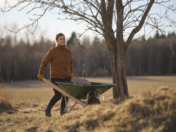 Woman pushing wheelbarrow in field