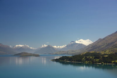 Scenic view of sea and mountains against clear blue sky