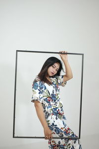 Portrait of young woman sitting against wall