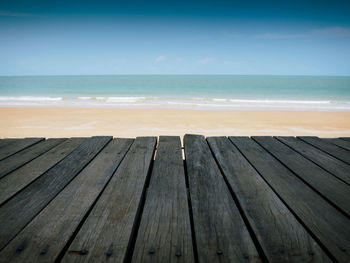 Wooden pier on beach against sky