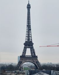 Communications tower in city against sky