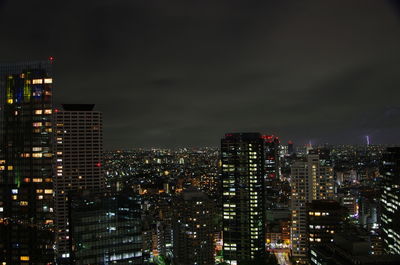 Illuminated buildings in city against sky at night