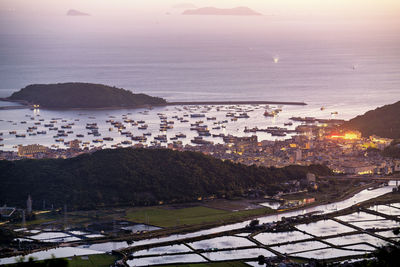 High angle view of townscape by sea against sky during sunset