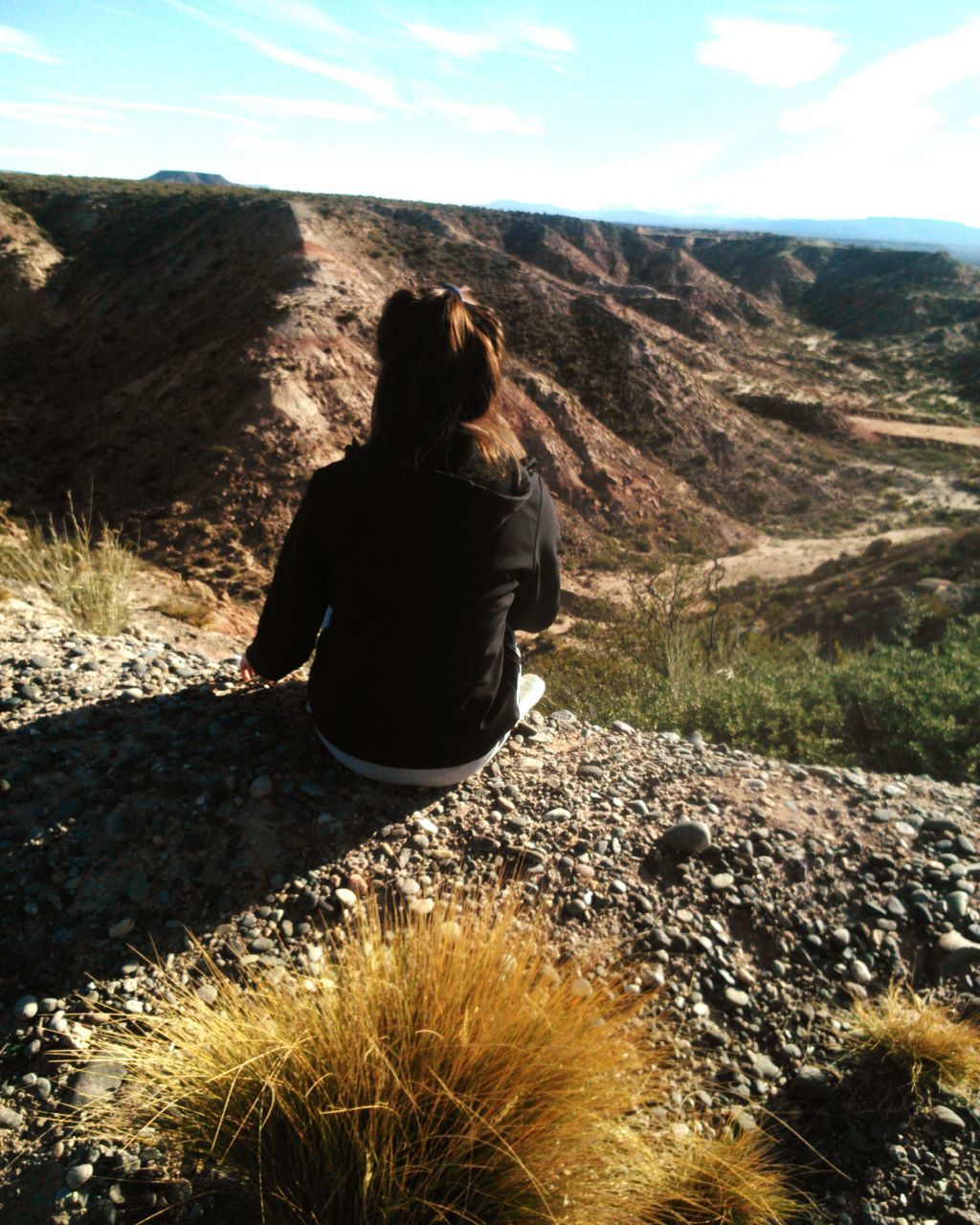 REAR VIEW OF WOMAN STANDING ON MOUNTAIN LANDSCAPE