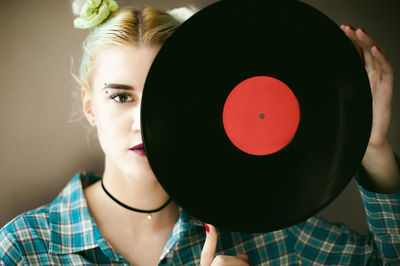 Portrait of young woman holding vinyl record while standing at home