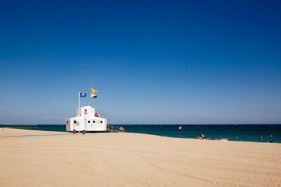 Life guard hut on beach against clear blue sky
