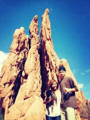 lifestyles, leisure activity, rock - object, blue, low angle view, rock formation, sky, clear sky, nature, sunlight, mountain, day, men, vacations, standing, beauty in nature, tranquility, young adult