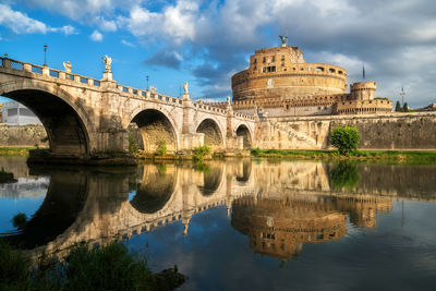 Arch bridge over river against cloudy sky