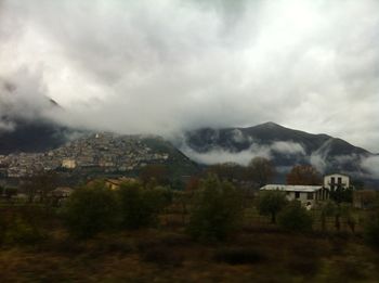 Houses on mountain against cloudy sky