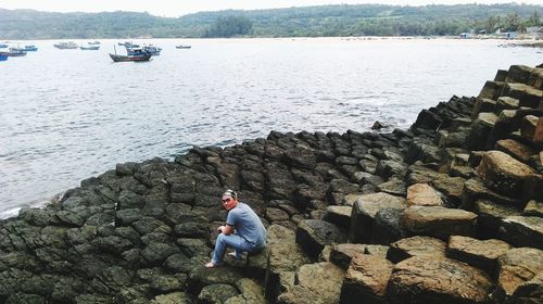 Man sitting on rock at beach