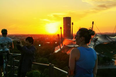 Rear view of people standing against orange sky