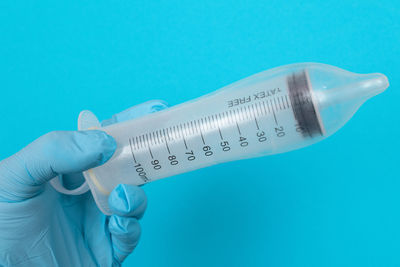 Close-up of hand holding blue over white background