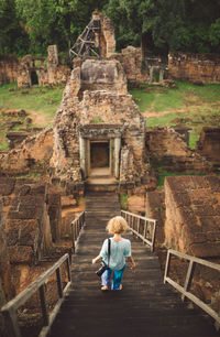 Rear view of woman walking on steps against old ruins