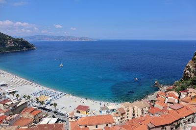 High angle view of townscape by sea against blue sky