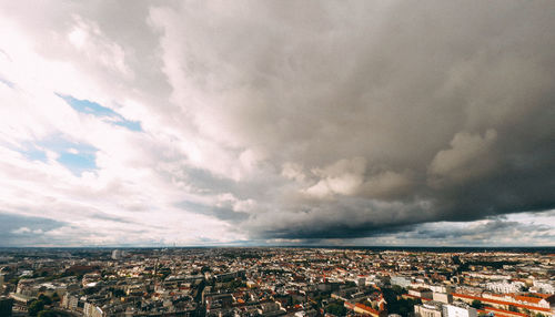 Aerial view of cityscape against cloudy sky