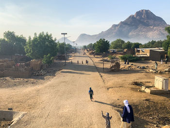 Rear view of people walking on mountain against sky