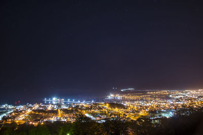 Illuminated cityscape against clear sky at night