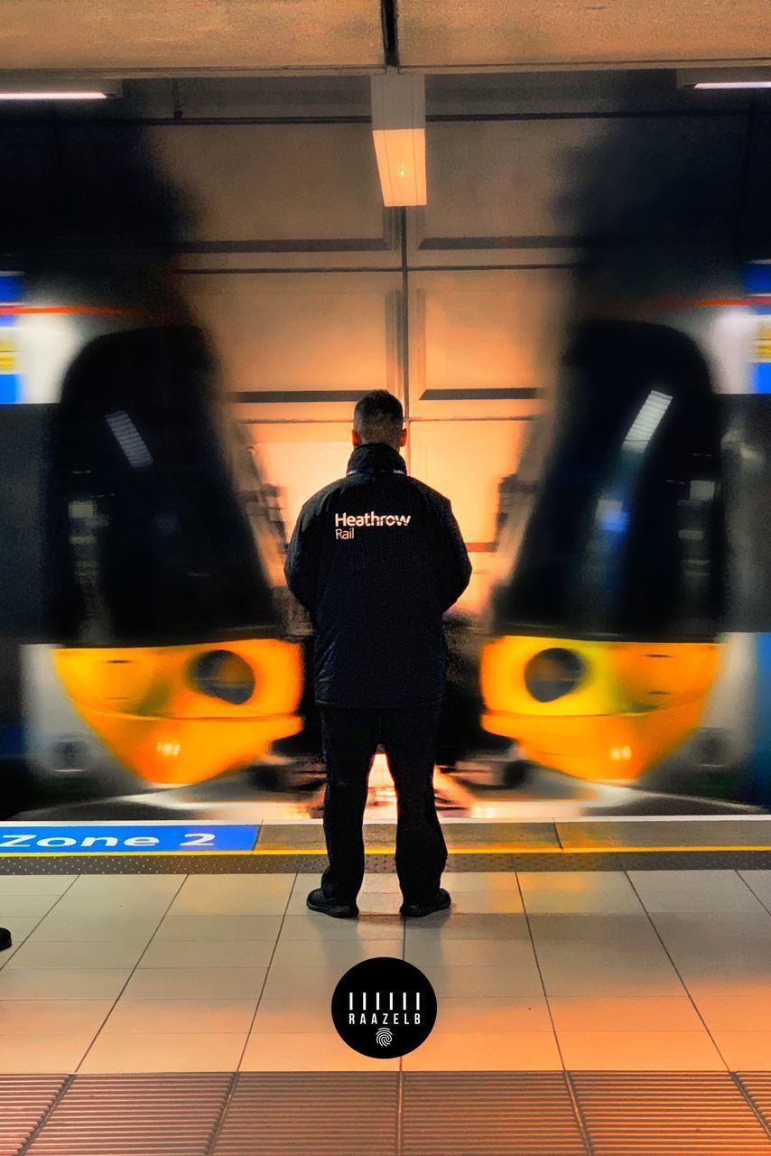 REAR VIEW OF MAN STANDING AT SUBWAY TRAIN
